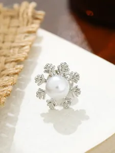 Nahaufnahme einer eleganten silbernen Schneeflocken-Brosche mit einer weißen Perle