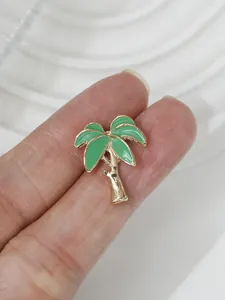 Nahaufnahme einer tropischen Brosche mit grüner Emaille-Palme und goldenem Metallrand