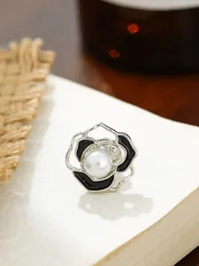 Detaillierte Makroansicht einer eleganten Kamelienblüten-Brosche mit schwarzer Emaille und Perle