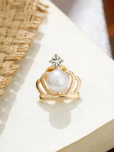 Detailansicht einer goldenen Kronen-Anstecknadel mit weißer Perle und glitzerndem Strassstein