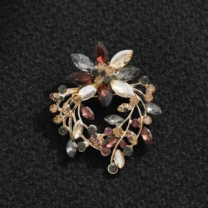 Elegante Blumenkranz-Brosche mit funkelnden bunten Strasssteinen auf schwarzem Stoff.