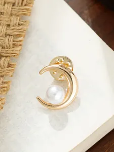 Nahaufnahme einer eleganten goldenen Mondbrosche mit einer zentralen weißen Perle
