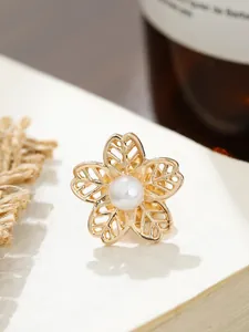 Detailaufnahme einer eleganten goldenen Kamelienblüten-Brosche mit Perle.