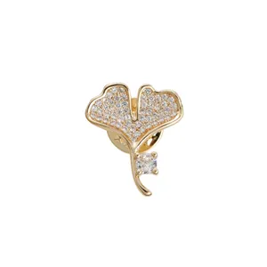 Vintage Ginkgo-Blatt-Brosche in Gold mit funkelndem Kristall-Pavé auf weißem Grund