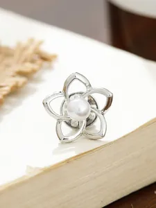 Detailansicht einer eleganten silbernen Kamelienbrosche mit einer weißen Perle