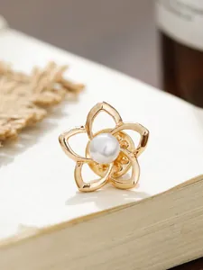 Detaillierte Nahaufnahme einer eleganten goldenen Kamelienbrosche mit einer weißen Perle.