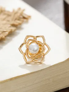 Detailansicht einer eleganten goldenen Kamelien-Anstecknadel mit Perle auf Papier