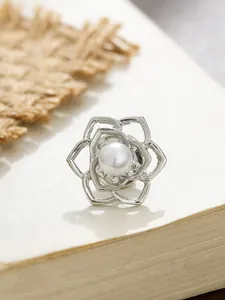 Nahaufnahme einer eleganten silbernen Kamelienblütenbrosche mit zentraler weißer Perle