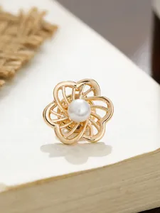 Detailansicht einer goldfarbenen Kamelien-Brosche mit einer glänzenden weißen Perle im Zentrum.