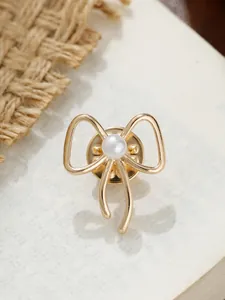 Nahaufnahme einer eleganten goldenen Brosche in Schleifenform mit weißem Perlendetail
