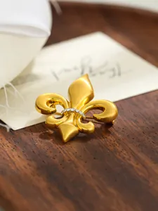 Detailed view of vintage gold fleur-de-lis brooch with rhinestone center for suits