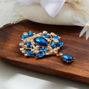 Vintage gold alloy brooch with deep blue crystals and teardrop pendant