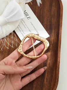Dettaglio della fibbia in lega d'oro irregolare per decorazione di cappotti e cinture