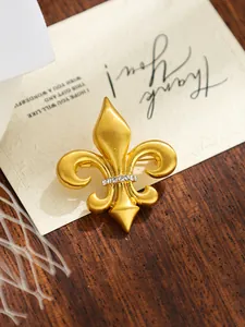 Detailed view of matte gold fleur-de-lis brooch with crystal inlay for suits