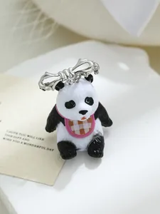 Gedetailleerde macro-opname van een 3D panda-bedel van hars met zilveren strik