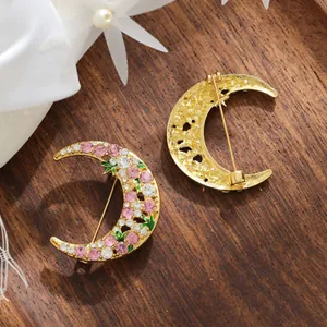 Elegant crescent moon brooch with pink and clear rhinestones on a wooden background