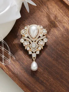 Gros plan d'une élégante broche vintage française avec strass et perle goutte