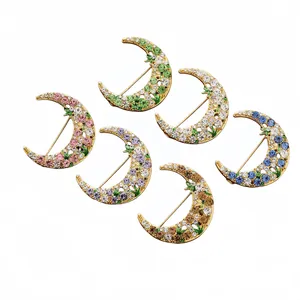 Set of six colorful rhinestone encrusted crescent moon brooches with floral details.