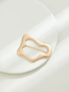 Dettaglio della fibbia irregolare in lega dorata per cappotti e cinture eleganti.