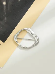 Dettaglio di una fibbia metallica argento irregolare per cappotti e cinture alla moda.
