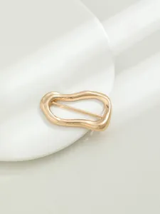 Macro della fibbia irregolare in oro con design ondulato lucido e barra di metallo