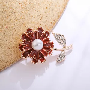 Detailed macro shot of a red enamel carnation brooch with a pearl and rhinestones
