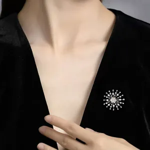 Detailed view of sparkling rhinestone snowflake brooch on elegant black velvet dress.