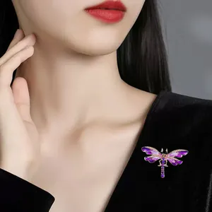 Detailed macro view of purple enamel dragonfly brooch on elegant black velvet dress.