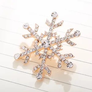 Detailansicht einer funkelnden Schneeflocken-Brosche mit Strasssteinen auf Goldbasis.