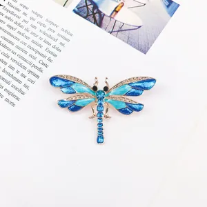 Close-up of a vintage dragonfly brooch with blue enamel wings and rhinestone details.