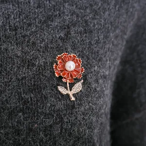 Close-up detail of a red carnation flower brooch with pearl pinned on grey knitwear