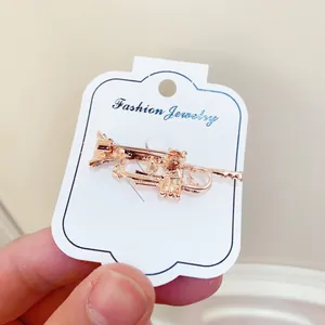 Detailed view of rose gold trumpet musical instrument brooch on display card