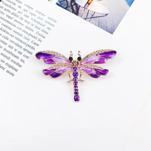 Detailed view of a purple enamel dragonfly brooch with gold-tone metal frame and crystals