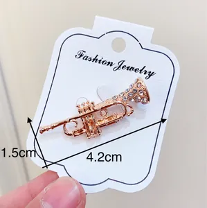 Detailed macro view of a gold-toned trumpet brooch with crystal accents and measurements