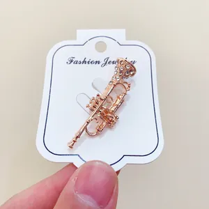 Elegant gold-tone trumpet-shaped musical instrument brooch with sparkling rhinestones
