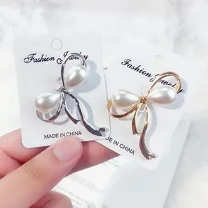 Detailansicht eleganter Schmetterlings-Perlenbroschen in Gold und Silber auf Karten