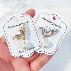 Nahaufnahme eleganter flügelförmiger Broschen mit Perlenanhängern und Glitzersteinen