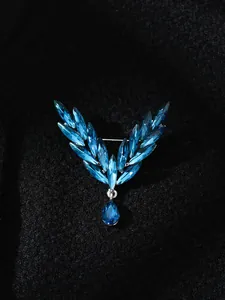 Detailed macro view of an elegant blue crystal angel wing brooch with a teardrop pendant
