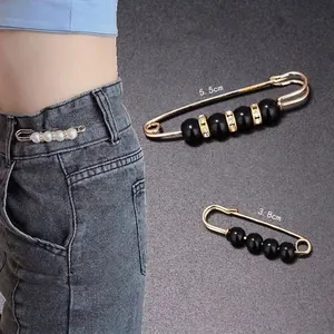 Detailansicht von zwei dekorativen Taillenverstellnadeln neben einem Modell in Jeans.