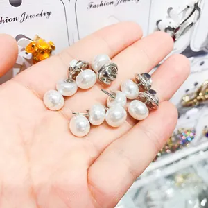 Macro view of small white pearl anti-exposure pins held in hand for clothing decoration.