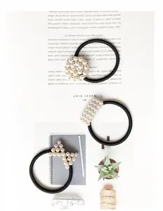 Detailed view of three elegant black elastic hair ties with diverse pearl designs