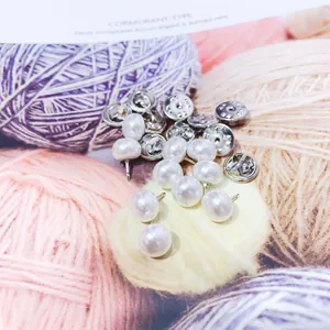 Close-up macro detail of elegant white pearl pins with silver-tone metal clutch backings