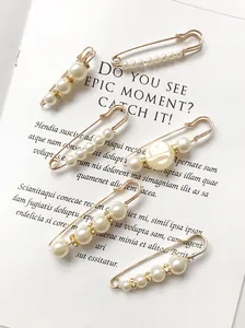 Detailansicht goldener Sicherheitsnadeln mit eleganten weißen Perlenakzenten.