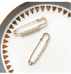 Nahaufnahme eleganter goldfarbener Sicherheitsnadel-Brosche mit glänzenden Perlen
