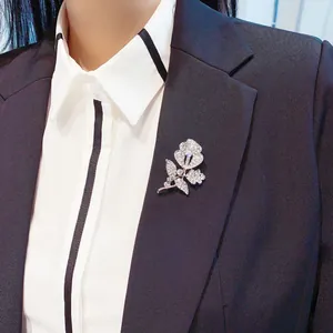 Detailansicht einer funkelnden silbernen Strass-Blumenbrosche an einem Blazer-Revers.