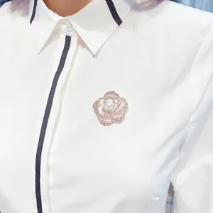 Detaillierte Makroansicht einer eleganten Kristall-Rosen-Brosche auf einer weißen Bluse
