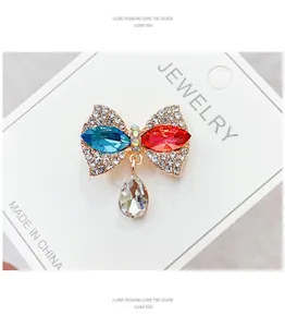 Macro detail of a sparkling bow brooch with red and blue rhinestones on a white card board