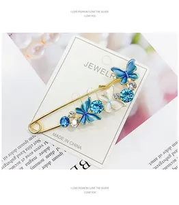 Detailansicht einer goldfarbenen Schmetterlingsbrosche mit blauem Email und Steinen