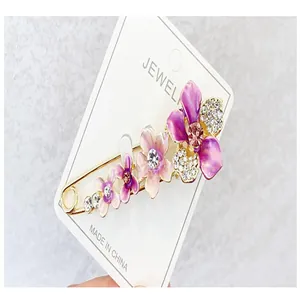 Detailansicht einer eleganten Blumenbrosche mit lila Emaille und funkelnden Kristallen