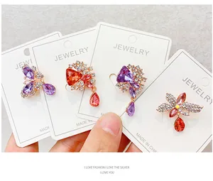 Close-up of elegant crystal rhinestone brooches with colorful stones on jewelry cards.